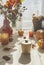 Delivery soup container on table with beige tablecloth, burning candle, pumpkins, autumn flower bouquet, cinnamon and autumn