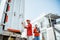 delivery workers standing near container door against white building background