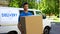 Deliveryman holding big cardboard box, household appliances transportation
