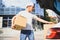 Deliveryman holds parcels at the car, delivering