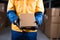 Deliveryman, latex gloved, holds smartphone and a cardboard box for delivery