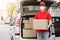 Deliveryman takes parcels from trunk of car