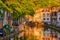 Delt canal with old houses and cars parked along on sunset