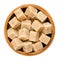 Demerara brown sugar cubes in wooden bowl over white