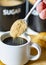 Demerara sugar falling from a silver teaspoon into a small cup of hot espresso coffee,in a domestic kitchen,Worcestershire,United