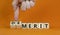 Demerit or merit symbol. Businessman turns wooden cubes and changes words `demerit` to `merit`. Beautiful orange background, c