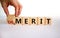 Demerit or merit symbol. Male hand flips the wooden cube and changes words `demerit` to `merit`. Beautiful white background, c