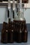 Demijohn fulled of fermented beer with airlock and dark brown bottles