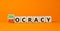 Democracy or autocracy symbol. Turned wooden cubes and changed the concept word Autocracy to Democracy. Beautiful orange