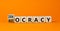 Democracy or autocracy symbol. Turned wooden cubes and changed the concept word Autocracy to Democracy. Beautiful orange