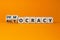 Democracy or autocracy symbol. Turned wooden cubes and changed the word autocracy to democracy. Beautiful orange background, copy