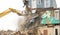 Demolishing a building with a large backhoe