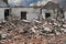 Demolishing site with ruined house and heap with bricks