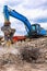 Demolition excavator separating irons and concrete on construction site