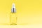 Demonstrating trendy color of 2021 - Yellow. Glass transparent mockup bottle with dropper with cosmetic serum, oil, on pastel pink