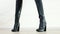 Demonstration of black smooth leather boots on high heels with silver long zipper in the middle