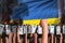 Demonstration stopping concept - protest in Ukraine on flag background, police squad stand against the protesting crowd -