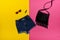 Denim shorts, black handbag, lipstick and glasses. Bright yellow and pink background. Fashionable concept