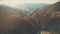 Dense brown forests cover hilly landscape lit by autumn sun