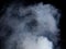 Dense Fluffy Puffs of White Smoke and Fog on black Background, Abstract Smoke Clouds, Movement Blurred out of focus. Smoking blows