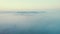 Dense, heavy, thick fog softly covering hills and forests. Sunrise light. Drone aerial bird's eye perspective