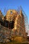 Dense scaffolding on southern walls of medieval Hrusov castle, sunlit by late afternoon winter sunshine.