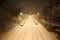Dense snowfall and empty road at night