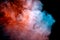 A dense, swirling cloud of colorful smoke against a black background, highlighted in red and blue in waves from the vape