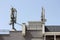 Densely mounted multiple cell phone transmitters and antennas on strong metal pole on top of newly built apartment building with