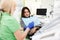 Dental clinic doctor shows a panoramic x-ray picture to his patient.  Doctor explains to her patient the condition of her teeth