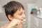 Dental education in the family, a boy with joy 10 years old, washing his teeth with toothpaste and a toothbrush in the bathroom.