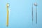 Dental instruments. Dental mirror, probe hook and toothbrush with floss on blue background. Copy space