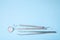 Dental instruments. Dental mirror, probe hook, tweezers on blue