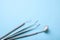 Dental instruments. Dental mirror, probe hook, tweezers on blue background