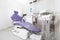 A dental surgery room with a dental chair with purple upholstery