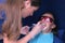 Dentist applying gel for LED whitening to woman patient`s teeth in dentistry.