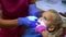 Dentist with assistant with tattooed hands repairing little girl child tooth