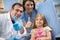 Dentist with assistant and young patient show thumb up