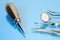 Dentist basic tools and elevator on blue glass table: dental mirror, kornzange, explorer, forceps. Dental therapy and healthcare