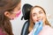 A dentist carefully doing a teeth grinding procedure to a graceful woman