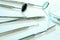 Dentist equipment: kornzange or forceps, two dental mirrors, cement spatula, explorer. Dental tools on white surface