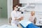 A dentist examines the oral cavity of her patient on the dentist`s chair with the help of a special medical appliance