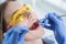 A dentist examines a patient, close-up of a patient with an open mouth next to which dental objects