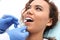 Dentist examining African-American woman`s teeth with mirror