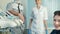 Dentist with his assistant stand near happy patient in special chair.