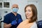 A dentist is holding a dental mirror and dental explorer near a female patient