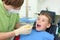 Dentist looks at teeth of boy in dental clinic