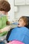 Dentist looks at teeth of girl in dental clinic