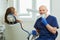 Dentist lowered medical face mask and smiles, holds a dental drill near patient