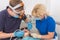 Dentist in mask with loupe binocularsand assistant working on patient